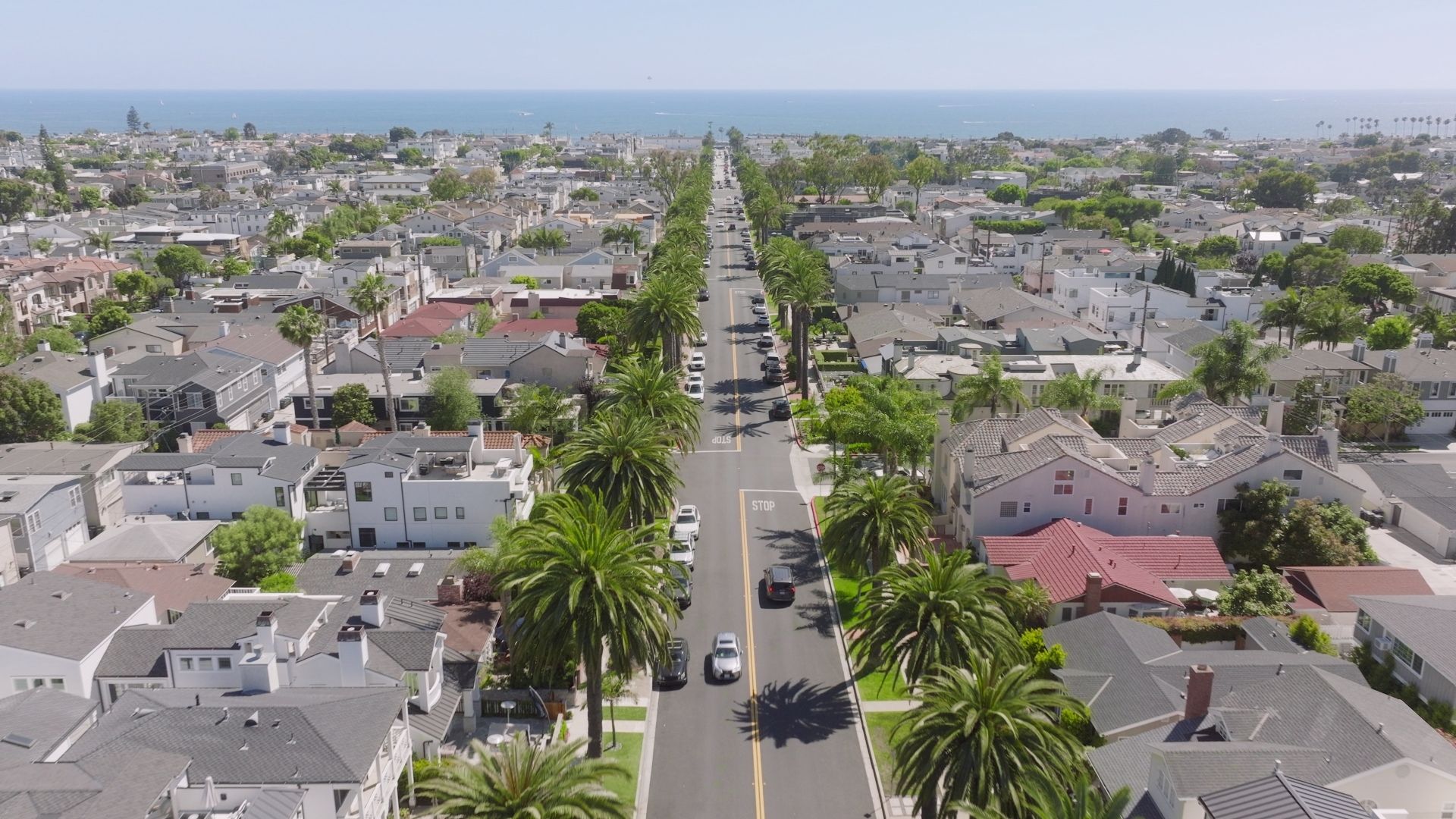 A palm-lined Corona del Mar residential street leading toward the Pacific Ocean